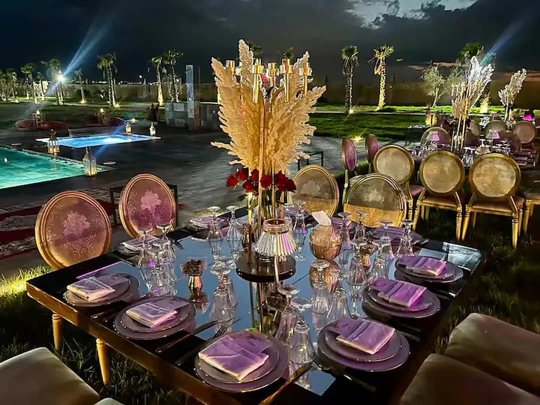 Une table de gala dressée aux Domaines du Sahara, vaisselle dorée et piscine éclairée en fond