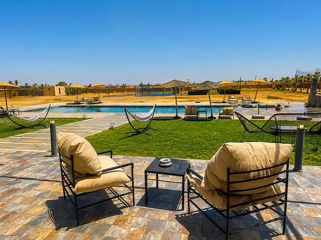 La terrasse des Domaines du Sahara, ses fauteuils et ses hamacs face à la piscine et à la plaine