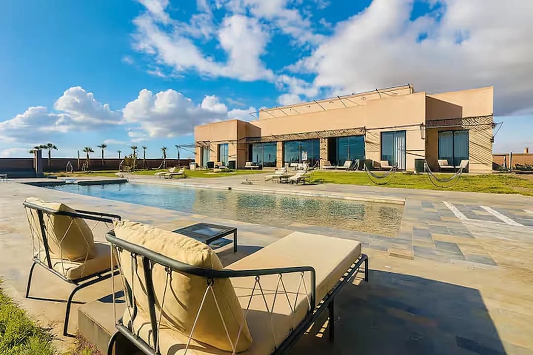 La villa des Domaines du Sahara et sa piscine en plein jour, sous le ciel de Marrakech